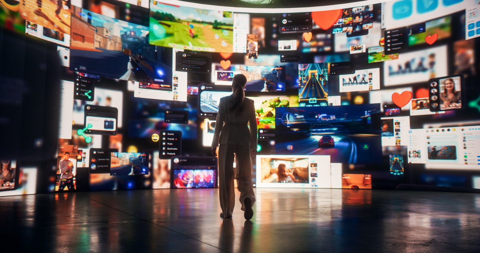 A person stands in a dark room surrounded by large, curved digital screens displaying various images, videos, and social media content, creating an immersive, futuristic environment.